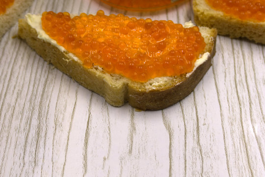 Red caviar salmon roe on a slice of bread and butter .