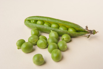Many single fresh green peas and one pod