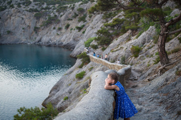 a girl in a blue dress admires nature in the Bay of the Black sea in the Crimea on the Golitsyn trail. tourism, recreation and sightseeing on the beach