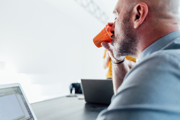 View over shoulder of man drinking from plastic cup
