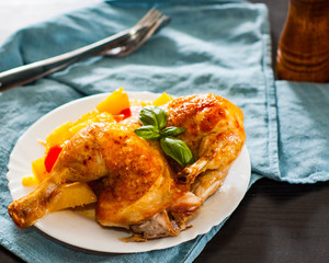 roasted half chicken with carrots, onions and potatoes served on a white plate on table
