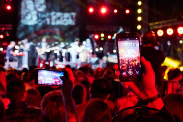 Fototapeta na wymiar Hand with a smartphone records live music festival, live concert, happy youth