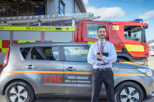 Portrait Of Fire Chief In Fire Station With Electric Car