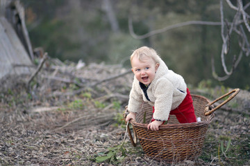 Petit bébé garçon se met debout dans un panier comme si c'était son bateau. Jeux d'enfants