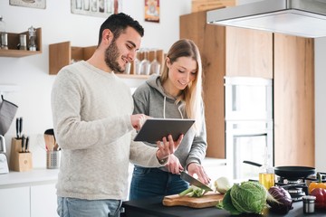 Couple preparing food using digital tablet