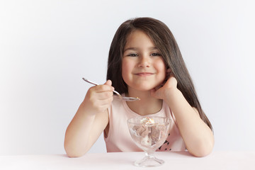 Happy child girl eating ice cream in white and chocolate bowl on white background. Enjoying delicious.