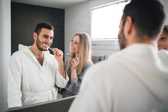 Mirror image of couple brushing teeth in bathroom