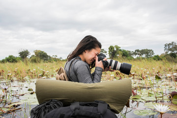 Young female tourist photographing Okavango Delta, Botswana, Africa