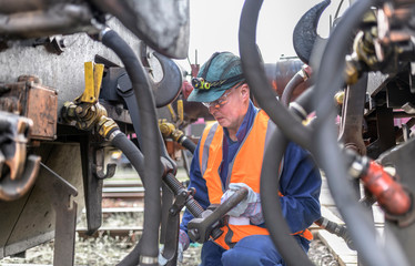 Engineer hitching one locomotive to another in train engineering factory