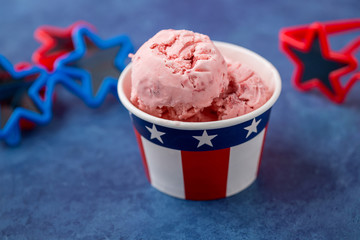 Homemade Strawberry Ice Cream in Red, White, and Blue Paper Cups with Red and Blue Star-shaped Sunglasses on a Blue Background