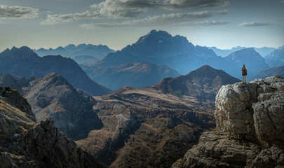 Climber on cliff looking at mountain ranges, Dolomites, Cortina d'Ampezzo, Veneto, Italy