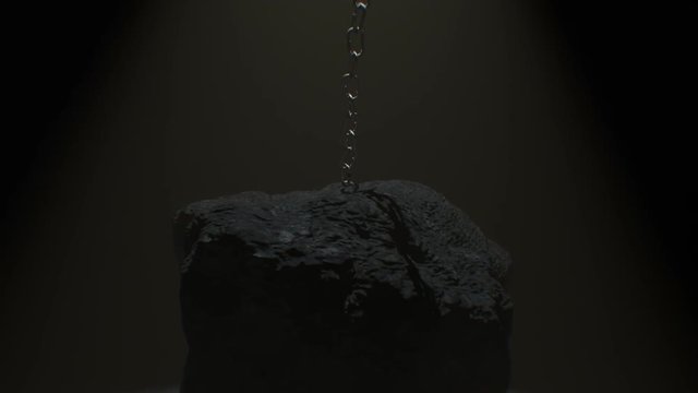 Close up of metal chain attached to a large boulder or rock is lifted up and pull strongly against the confinement, eventually breaking free with a small explosion.
