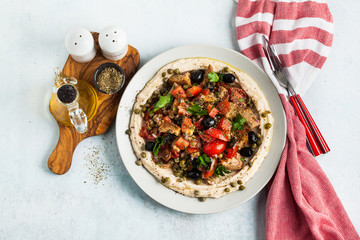 vegan panzanella salad on a layer of hummus on a plate. tasty healthy food.