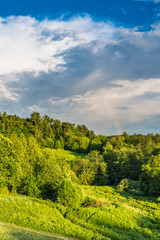 Fototapeta na wymiar Beautiful landscape with forest and hills and a rainbow in the sky