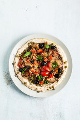 fresh Greek dakos salad on a layer of hummus. light vegan summer nutritious recipe