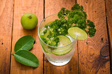 Lime, cucumber, parsley cocktail, lemonade, detox water with ice cubes in a glasses on wood