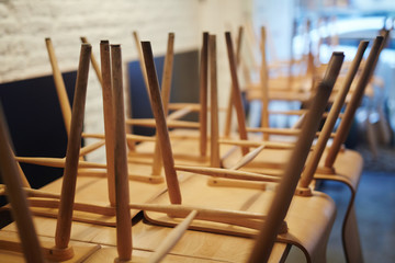Close-up view of wooden chairs stacked upside down on table in closed restaurant