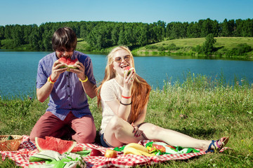 Happy couple on picnic eating watermelon,having fun together. outdoor portrait on lake