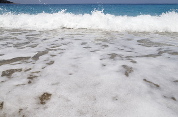 Background of white foam wave on a sea pebble shore and a thin horizon line