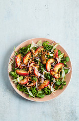 summer, very tasty salad with peaches, sweet onions and arugula with almonds on a table in a plate. simple healthy recipe