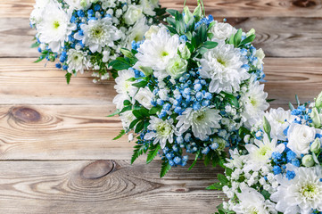 Fototapeta na wymiar Wedding bouquets bridesmaids in white and blue chrysanthemums on a wooden background. Top view