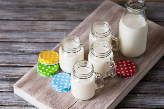 Milk jars with colorful caps on a cutting board 