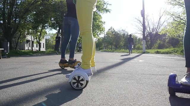 Young girls have fun eating sweet cotton candy riding gyroboards in a park slow motion