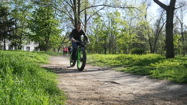Young man riding Electric bike in a park slow motion