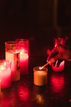 Mano encendiendo velas de colores  en una iglesia