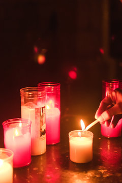 Mano encendiendo velas de colores en una iglesia