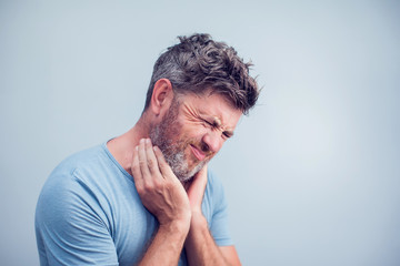 Obraz premium People, healthcare and problem concept - unhappy man touching his neck and suffering from throat pain over gray background