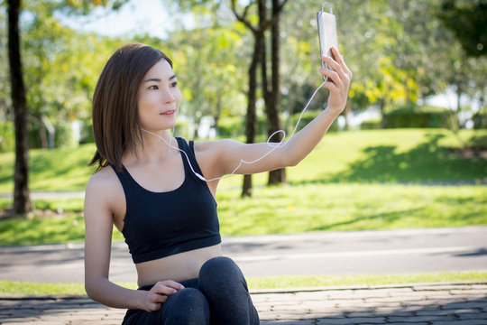 Girl sitting listening to music from a mobile phone and taking pictures during a workout session.