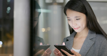 Business woman use of cellphone with window reflection at night