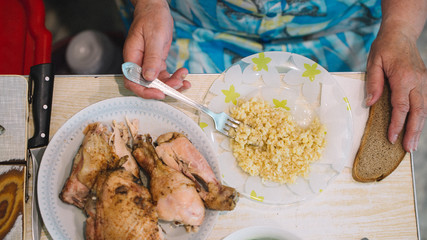 Homemade authentic russian ukrainian summer lunch at country side; salad with tomatoes and cucumbers and sour cream; porridge, baked chicken ; rural Eastern Europe