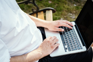 man sits on a bench and works on a laptop on holidays in the summer