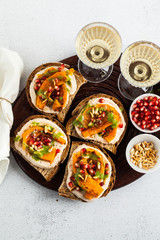 snack breads with hummus and baked pumpkin on a serving board with arugula pesto. seeds of pomegranate and pine nuts. healthy food