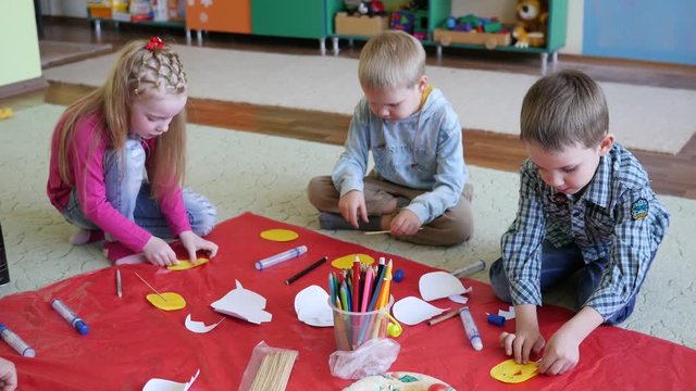 Woman educator entertain kids with paper handicraft game for fine motor skills