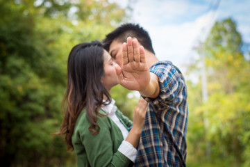 The man's hand concealed while he kissed the girl on a forest road.