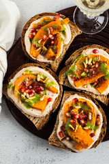 tasty bruschettes with hummus, baked pumpkin and arugula pesto on the table. vegan healthy food served with white wine