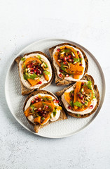 snack breads with hummus and baked pumpkin on a serving board with arugula pesto. seeds of pomegranate and pine nuts. healthy food
