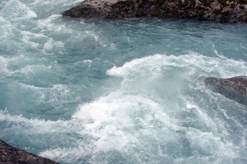 view of a crystal clear river flowing between the rocks from the melting glacier.