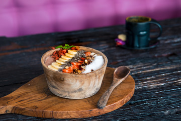 Superfood smoothie bowl on wooden rustic table. Raw vegan healthy eating, dessert food photography concept. Bright, vivid colors. Copyspace