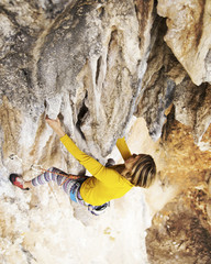 Woman rock climber. Rock climber climbs on a rocky wall. Woman makes hard move.