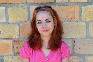 portrait of a girl with red hair on a brick wall background