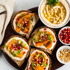 tasty bruschettes with hummus, baked pumpkin and arugula pesto on the table. vegan healthy food