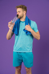 Man drink water after training on violet background. Thirsty sportsman with plastic bottle on...
