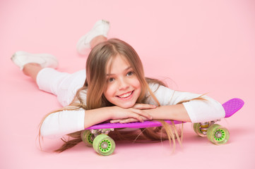 Obraz na płótnie Canvas Teens hobby concept. Girl likes to ride skateboard and sporty lifestyle. Girl on smiling face posing with penny board, pink background. Kid girl with long hair ready to ride penny board