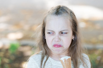 Sweet tooth girl child with white ice cream in waffle cone. Kid girl with ice cream cone in hand. Summer treats concept. Girl sweet tooth on disgusted face eats ice cream, light background