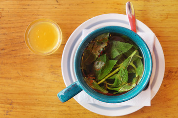 Cup of mint tea and jar of honey on wooden table, top view   