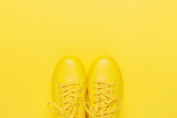 Pair of yellow shoes on yellow background. Trendy summer color, monochrome image. Hipster concept.